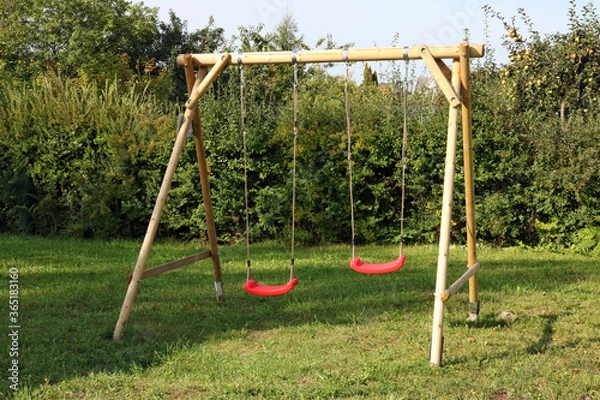 Fototapeta Children's swing made of logs and ropes and installed in the backyard of a rural house