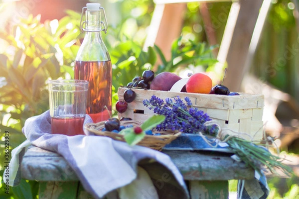 Fototapeta picnic in the garden with glass bottle of lemonade and fresh summer fruits