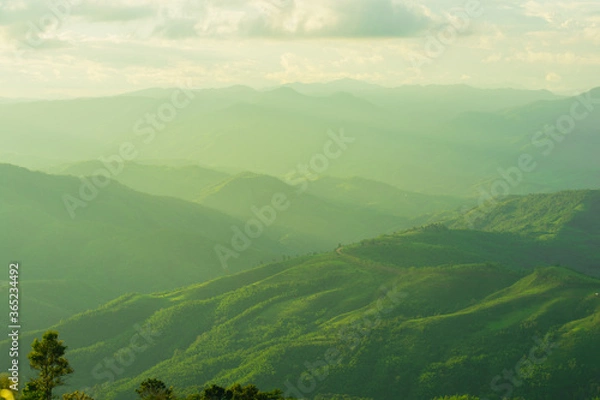 Fototapeta Sunset and mountains interspersed with green grass