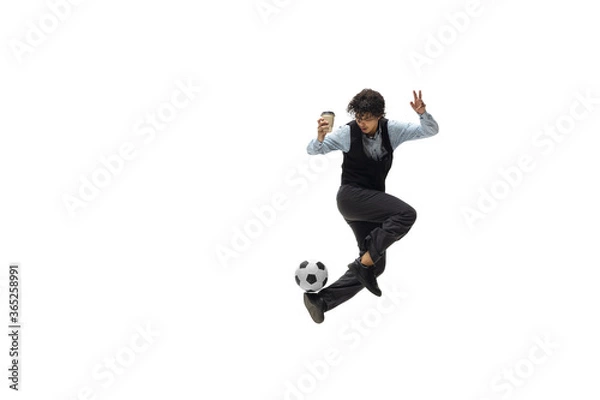 Fototapeta Man in office clothes playing football or soccer with ball on white background like professional player. Unusual look for businessman in jump kicking ball. Sport, healthy lifestyle, creativity.