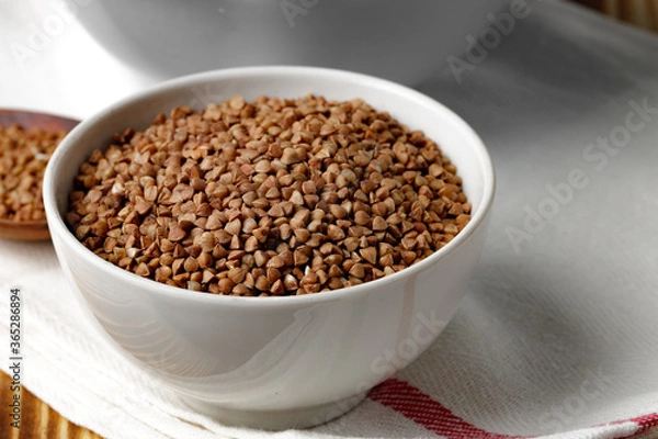 Fototapeta Bowl of raw uncooked buckwheat on wooden table