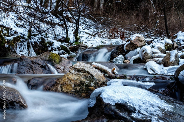 Obraz semi frozen small waterfall in a stream in the mountains in deep winter with ice