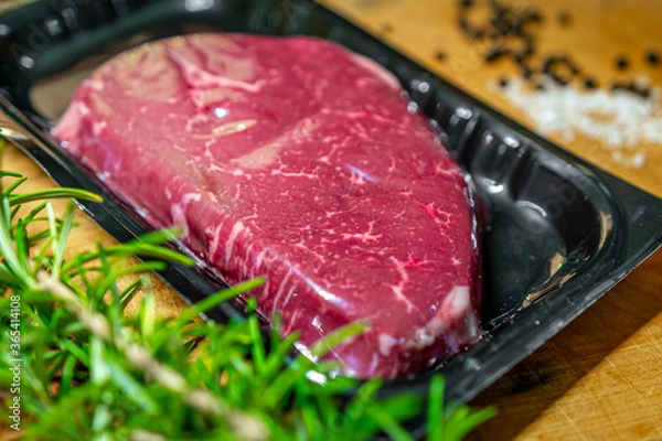 Fototapeta Beef steak in vacuum skin packaging and spices on wooden chopping board