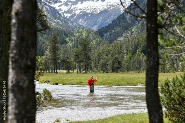 Obraz fly fisherman trout fishing with a hiking backpack and an orange jacket in the high mountains in summer