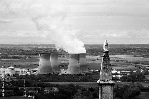 Obraz statue of holy watching smoking cooling towers of a nuclear power plant in the coutryside