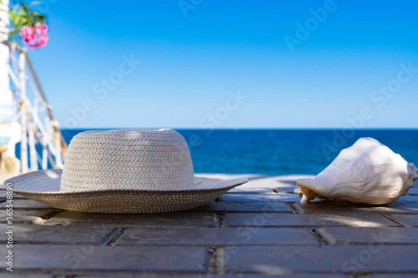 Fototapeta seashell and hat on the background of the blue sea