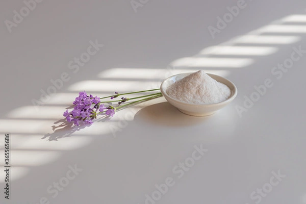 Fototapeta Selective focus to collagen powder in a white bowl and lavender sprigs on the table in morning shadow.
