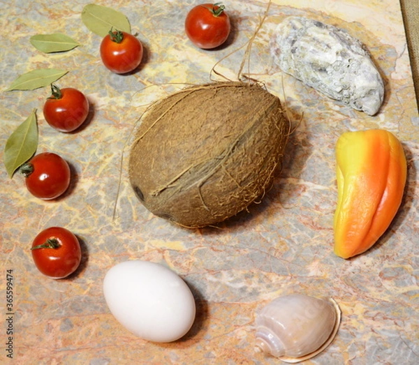Fototapeta vegetables, fruits, seashells and an egg on a marble surface: cherry tomatoes, bell peppers, bay leaves, oyster, shell, coconut and chicken egg