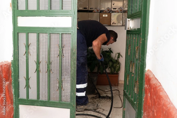 Fototapeta Worker cleans the drains hatch and removes dirt and debris from the sewer. Plumber cleans the sewer