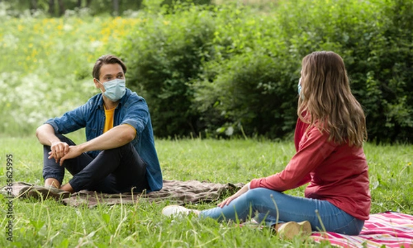 Fototapeta Couple have date during the coronavirus lockdown crisis. Man and woman in the park. Social distancing and virus protection.