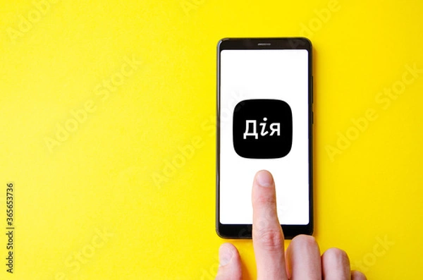 Fototapeta A male hand holds a smartphone, points a finger, types. Communication on a smartphone, correspondence. Place for text. Smartphone in hand on a yellow  background.