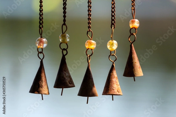 Fototapeta Wind chimes on chains hang off of a bird feeder