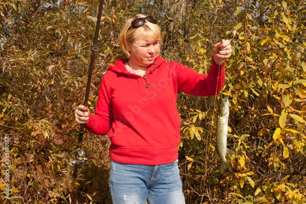 Obraz Woman with fishing rod and pike fish autumn
