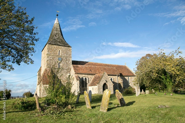 Fototapeta St Mary in the Marsh is an Anglican Church in New Romney - Kent. It has a traditional clock tower and spire which was added in the 15th century.