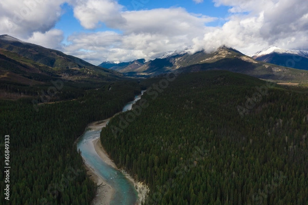 Obraz Aerial landscape over the Canadian Rocky Mountains in Yoho National in Canada with fluff white clouds in the blue sky and turquoise blue water and river crossing the valley over snowy mountain peaks. 