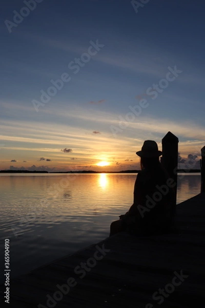Obraz silhouette of a woman sitting on a pier at sunset