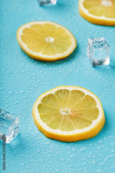 Fototapeta Slices of fresh lemon on a blue background with ice.