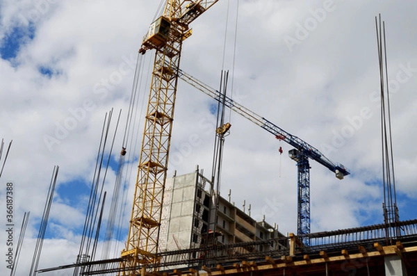 Fototapeta two construction cranes are building a high-rise building