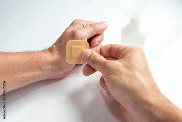 Fototapeta disinfecting the wound on the hand and applying a patch