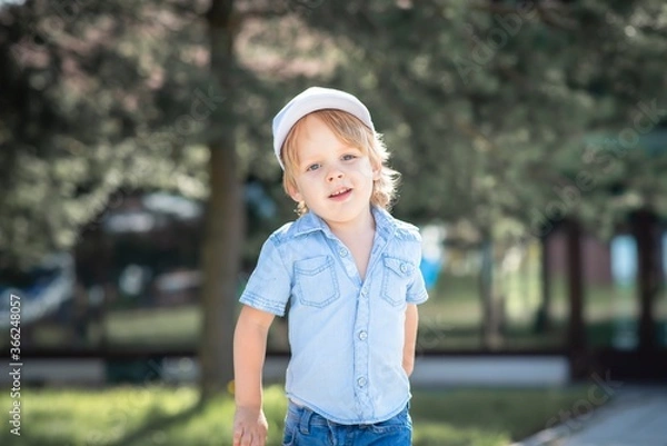 Obraz A boy in a white cap runs through the Park and smiles.