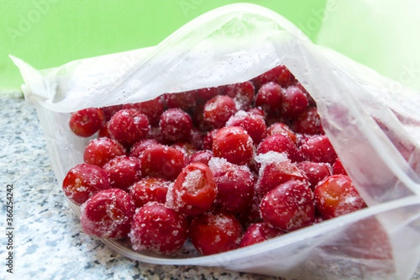 Fototapeta Frozen cherries in an open plastic bag from slightly above
