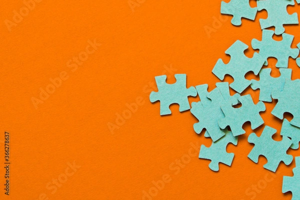 Fototapeta Puzzle. Many puzzle pieces on an orange background. The concept of collective thinking.