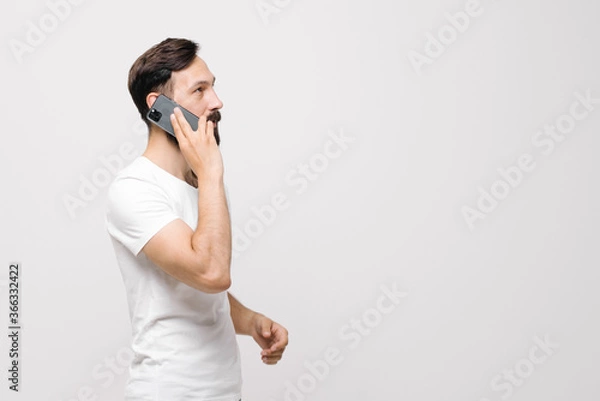 Fototapeta  Pensive young man is using a mobile phone. space for text