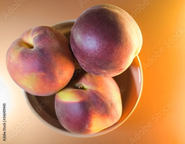 Fototapeta ripe peaches on a light yellow background, top view