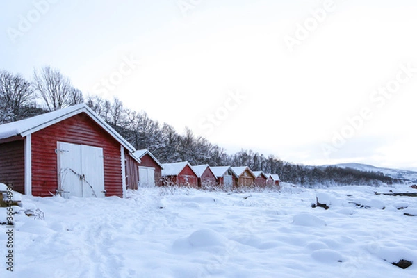 Obraz red typical houses in norway in winter. red wooden warehouses in scandinavia with white gates in the background of mountains