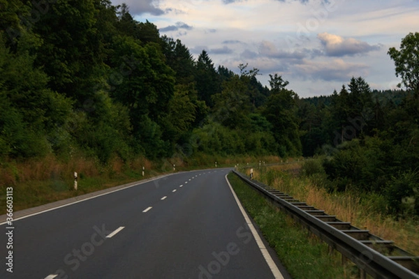 Fototapeta empty asphalt road in Odenwald forest in Germany. Asphalt road with leading lines in green environment.
