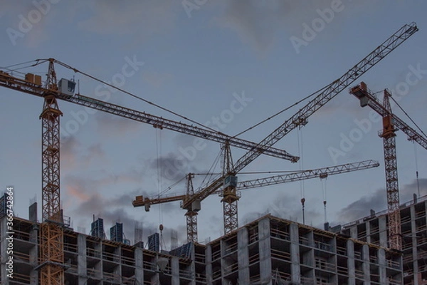 Fototapeta Construction site with cranes against the background of the evening sky