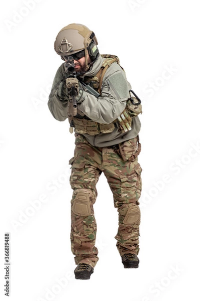 Fototapeta American soldier in military equipment with a rifle attacks on a white background, a commando with weapons in uniform, a ranger in action