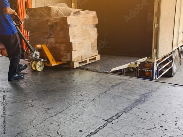 Fototapeta Worker driving forklift loading and unloading shipment carton boxes and goods on wooden pallet from container truck to warehouse cargo storage in logistics and transportation industrial 