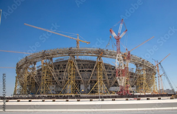 Fototapeta construction side of a football stadium with cranes and scaffoldings 
