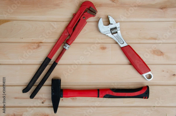 Fototapeta Tools for plumbing on a wooden background. Red wrench and hammer. Plumbing tools background.
