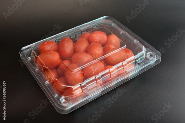 Obraz Tomatoes in plastic packaging placed on a black background
