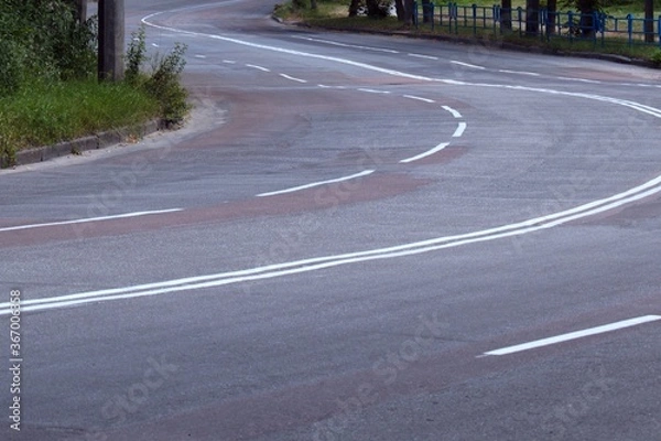 Fototapeta empty winding paved road with a marking of traffic lanes