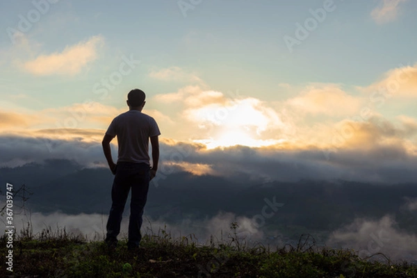 Fototapeta Young man looking beautiful view of foggy mountains landscape