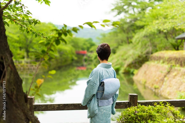 Fototapeta 城跡のお堀に立つ水色の着物を着たシニア女性