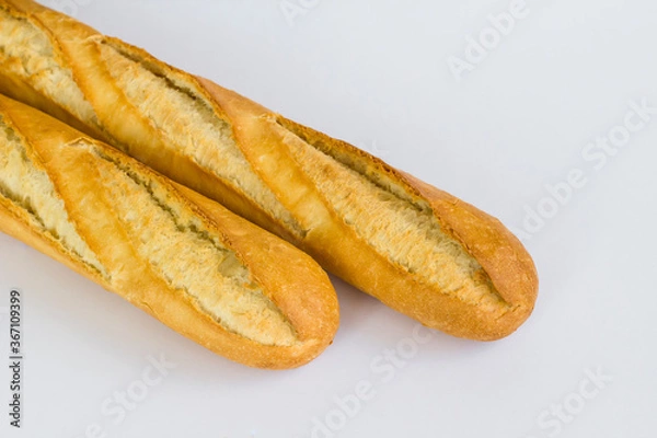 Fototapeta Fresh baguette breads on white surface with knife,above view.