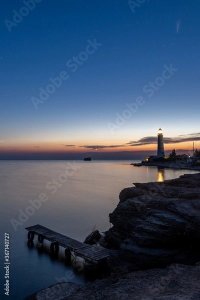 Fototapeta Panoramic HDR Landscape view of Neowise comet over white Lighthouse at night sky