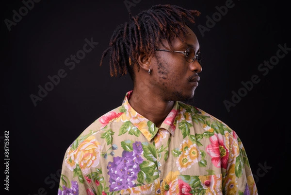Fototapeta Young African man with dreadlocks against black background