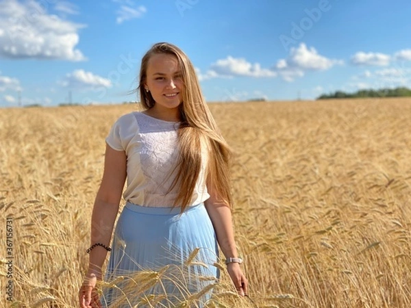 Obraz beautiful woman walks in a field with ears, takes pictures in a wheat field
