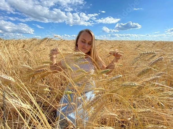 Obraz beautiful woman walks in a field with ears, takes pictures in a wheat field
