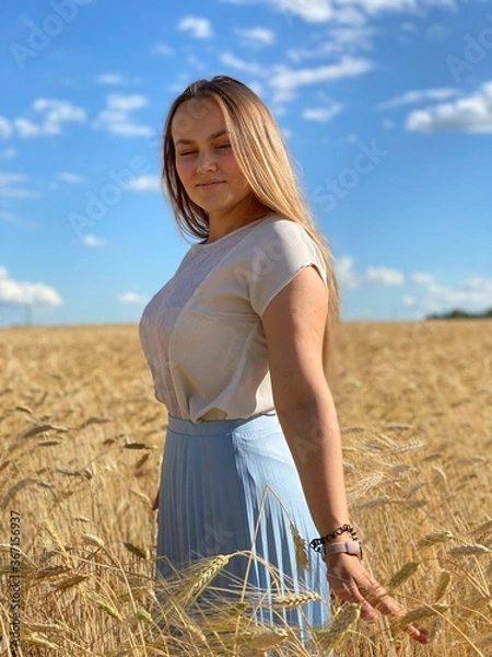 Obraz beautiful woman walks in a field with ears, takes pictures in a wheat field
