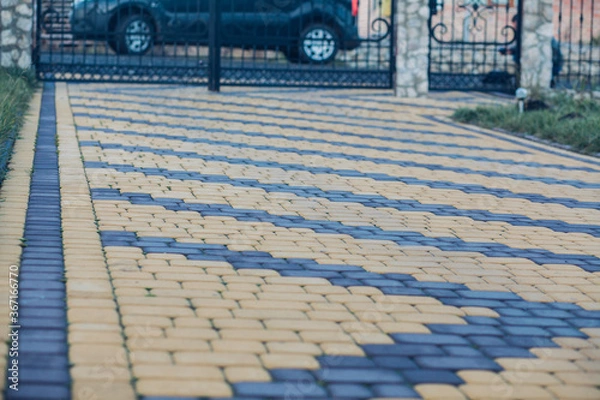 Fototapeta Nested pavers of various colors, around the grass is green, chic garden