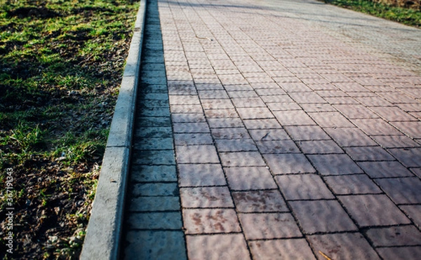 Fototapeta Nested pavers of various colors, around the grass is green, chic garden