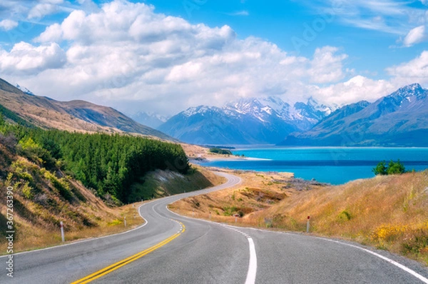 Fototapeta The winding road along the shore of Lake Pukaki, a glacial alpine lake in Mount Cook NP in New Zealand's South Island, set in a glacier-carved valley surrounded by snow-capped mountain peaks.