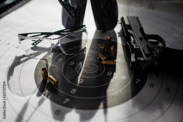 Obraz Shooting target with ammunition, pistol, ballistic glasses and headphones