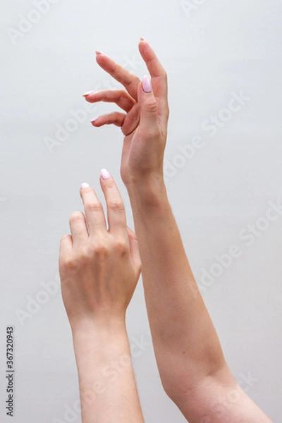 Obraz Crop view of a young woman's hands raising up close-up on a light monochrome background. Healthy hands and nails.